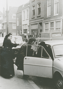 876927 Afbeelding van twee Zusters Augustinessen die een vrouw in een auto helpen, voor het Klooster Genazzano van de ...
